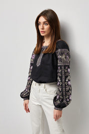 Black linen embroidered vyshyvanka blouse with Ukrainian symbolic ornament, worn by a woman.