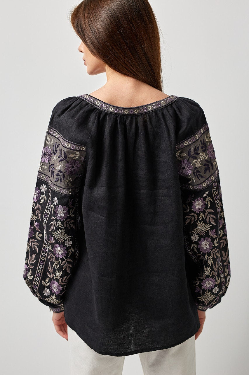 Back view of black linen Ukrainian vyshyvanka blouse with traditional embroidery on sleeves and back, showcasing symbolic design.