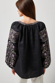 Back view of black linen Ukrainian vyshyvanka blouse with traditional embroidery on sleeves and back, showcasing symbolic design.