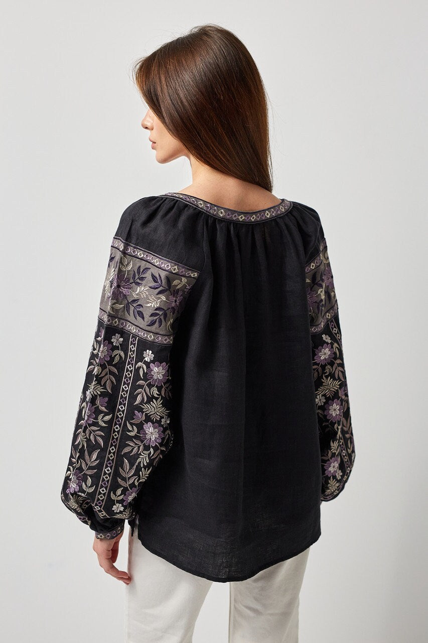 Back view of black linen Ukrainian vyshyvanka blouse with intricate embroidery, showcasing traditional symbolic ornament on sleeves and back.