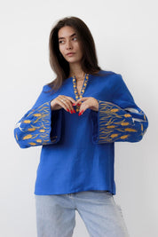 Woman wearing blue linen Ukrainian embroidered blouse with satin stitch ornament on sleeves