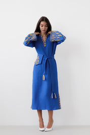 Woman wearing blue linen embroidered dress with Ukrainian boho Vyshyvanka folk style and vibrant sleeves.