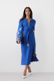 Woman wearing a blue linen embroidered dress in Ukrainian boho vyshyvanka folk style with vibrant ornamental details.