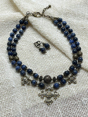 Handmade blue Ukrainian necklace with sodalite, bronze accents, and multilayer ethnic design on a textured surface.