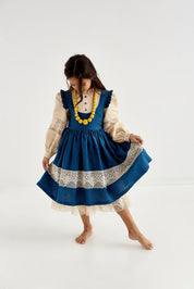 Girl wearing blue Ukrainian linen dress with lace trim, long puff sleeves, decorative necklace. Perfect for special occasions.