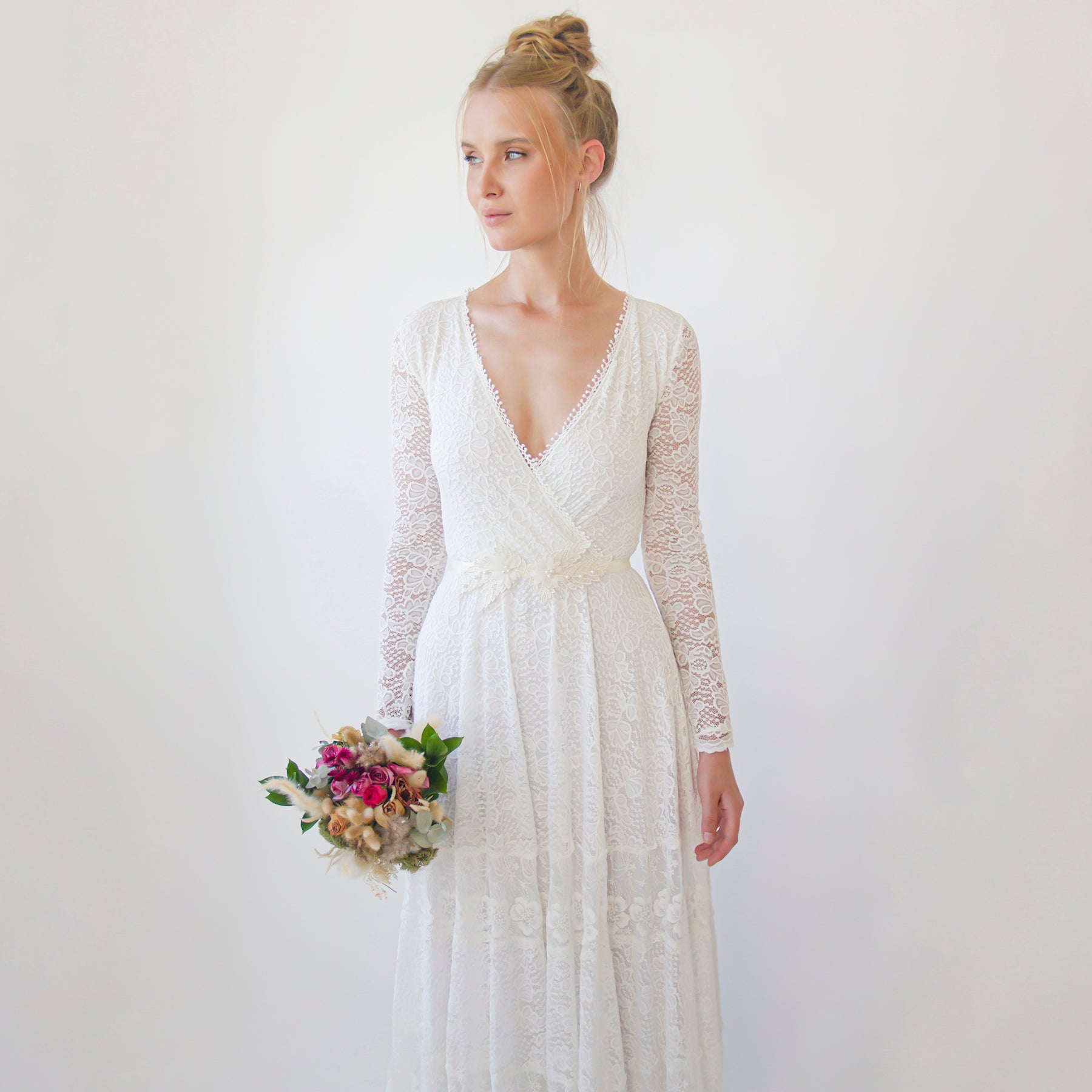 Bride in lace gown holding bouquet, wearing Isara Beaded Floral Sash, featuring hand-applied floral lace and shimmering beads.