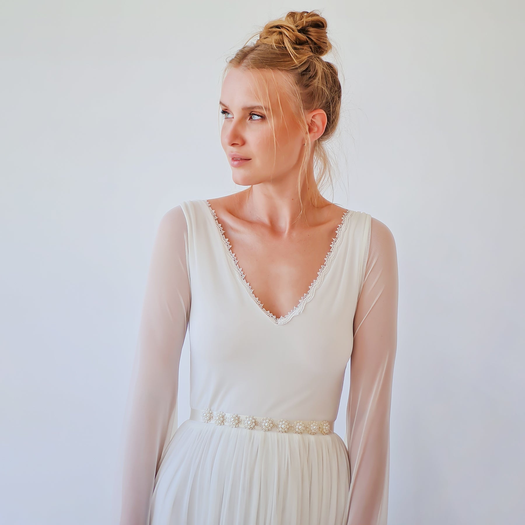 Bride wearing a white dress with Alurea Pearly Bridal Sash, featuring hand-applied beads and satin ties, adding elegant detail.
