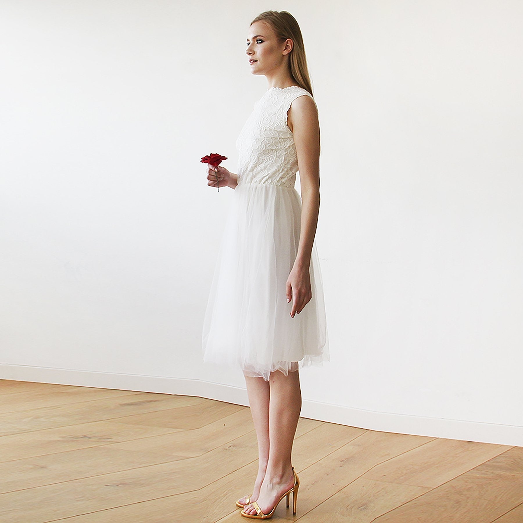 Woman in Evarelle Midi Lace Tulle Wedding Dress holding a red flower, showcasing open-back design and layered tulle skirt.