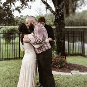 Couple in vintage-style wedding dress and checkered shirt embracing outdoors