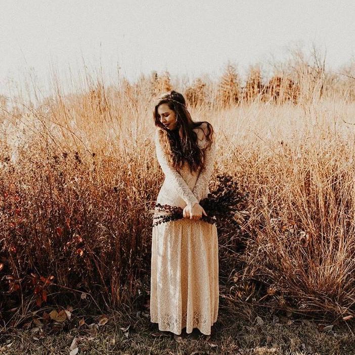 Bride wearing Elverin Medieval Lace Wedding Dress in a field, showcasing off-the-shoulder neckline and romantic lace sleeves.