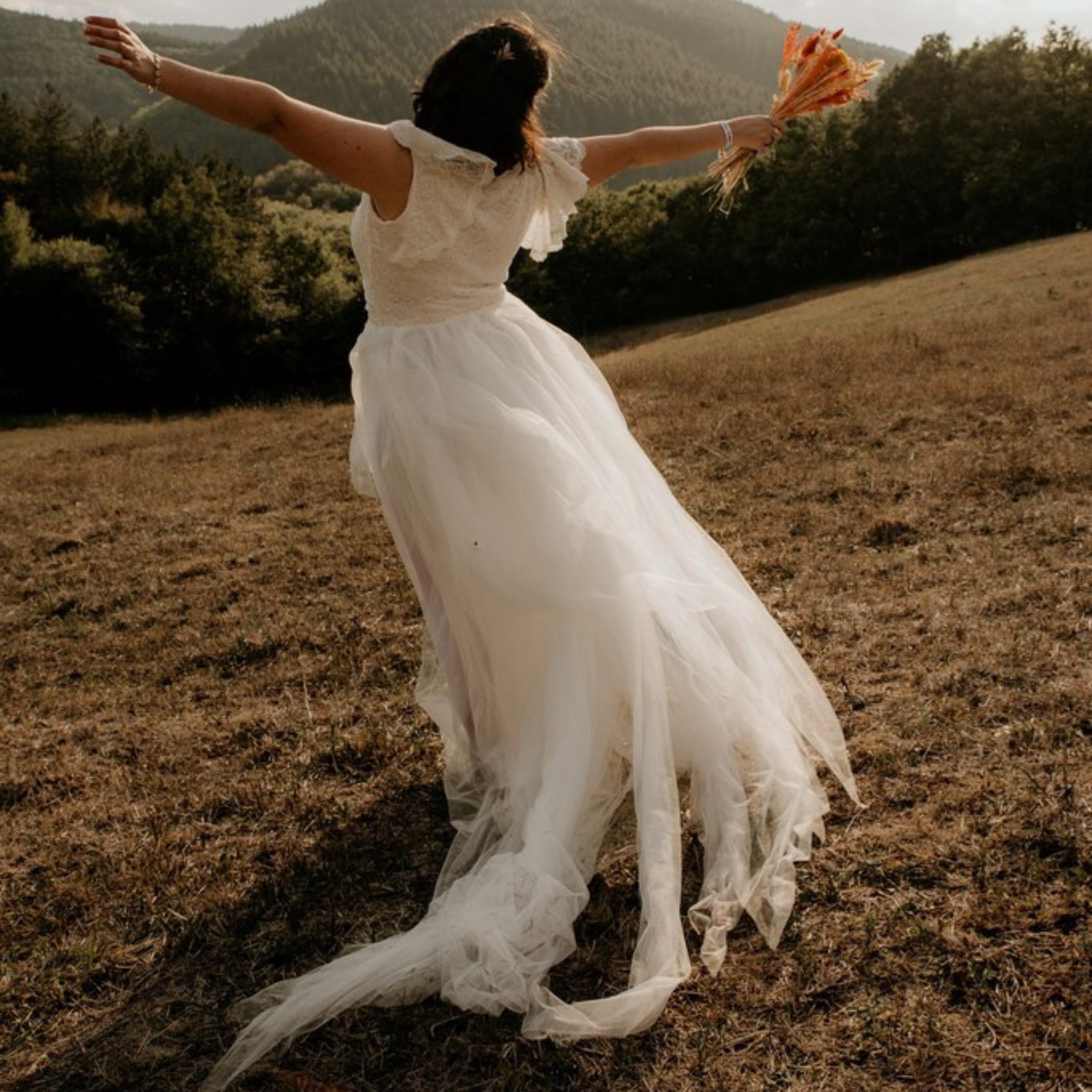 Bride in Selvienne Puffy Tulle Wedding Dress with flowing skirt, standing in a field, perfect for garden and barefoot ceremonies.