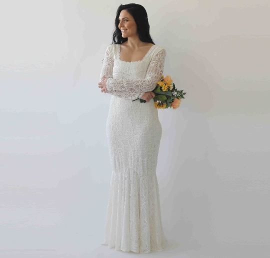 Woman wearing Elirelle Ivory Lace Wedding Dress with Sleeves, featuring a square neckline and mermaid silhouette, holding a bouquet.