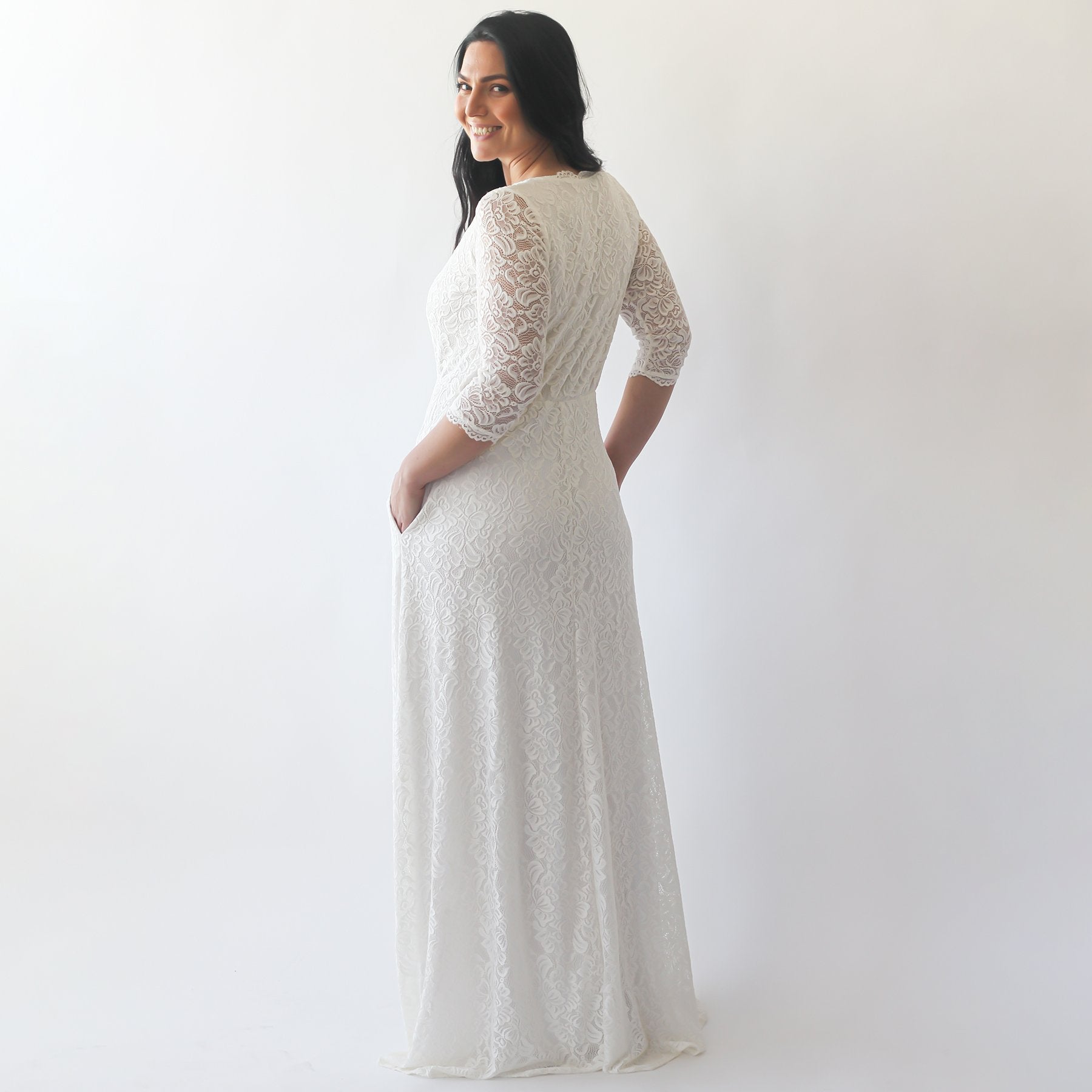 Plus-size model wearing Elyressa ivory lace boho gown with ¾ sleeves and pockets, featuring a flowy skirt perfect for weddings.