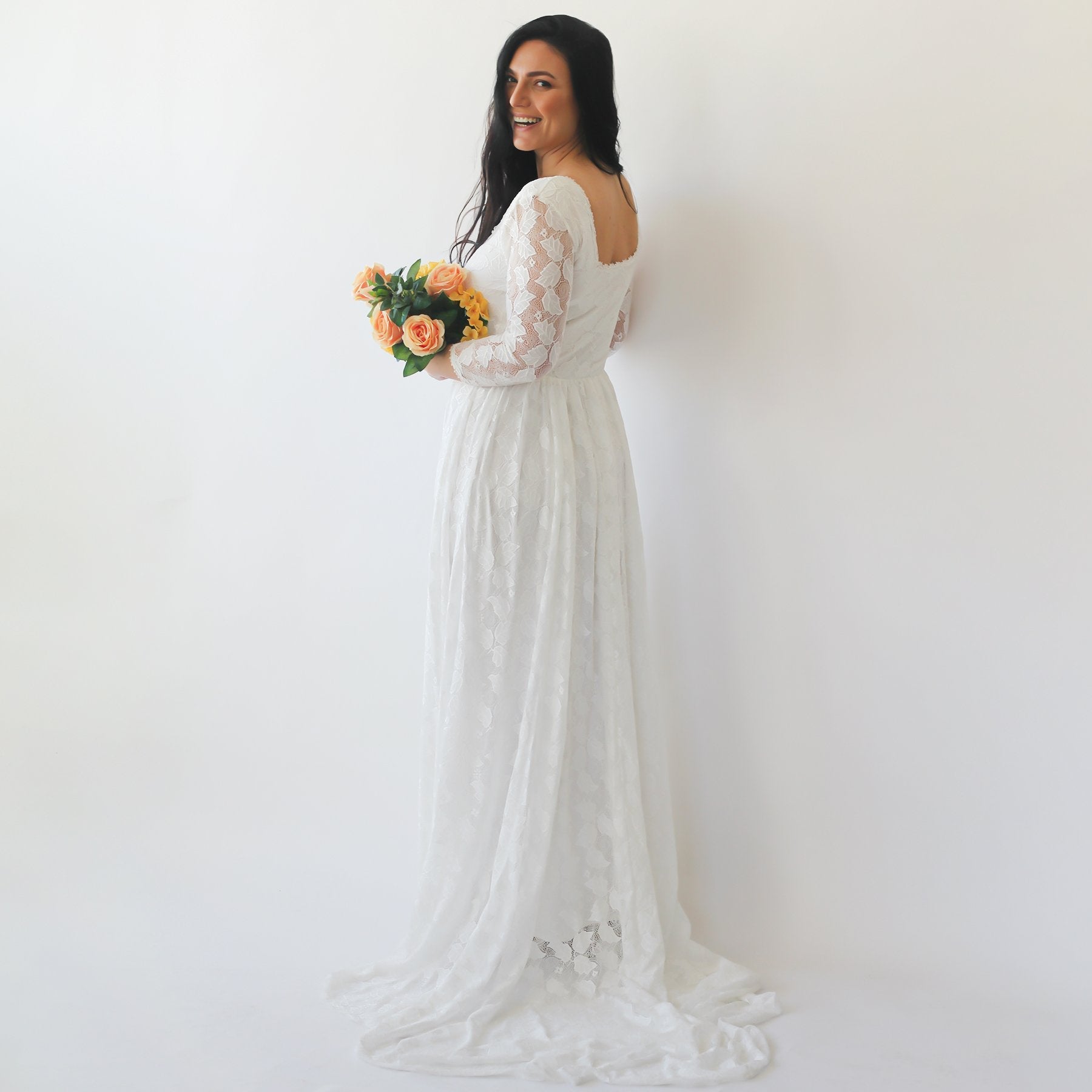 Woman wearing Leontelle Square Neck Wedding Dress with Train, holding a bouquet, featuring long sleeves and a flowing lace skirt.