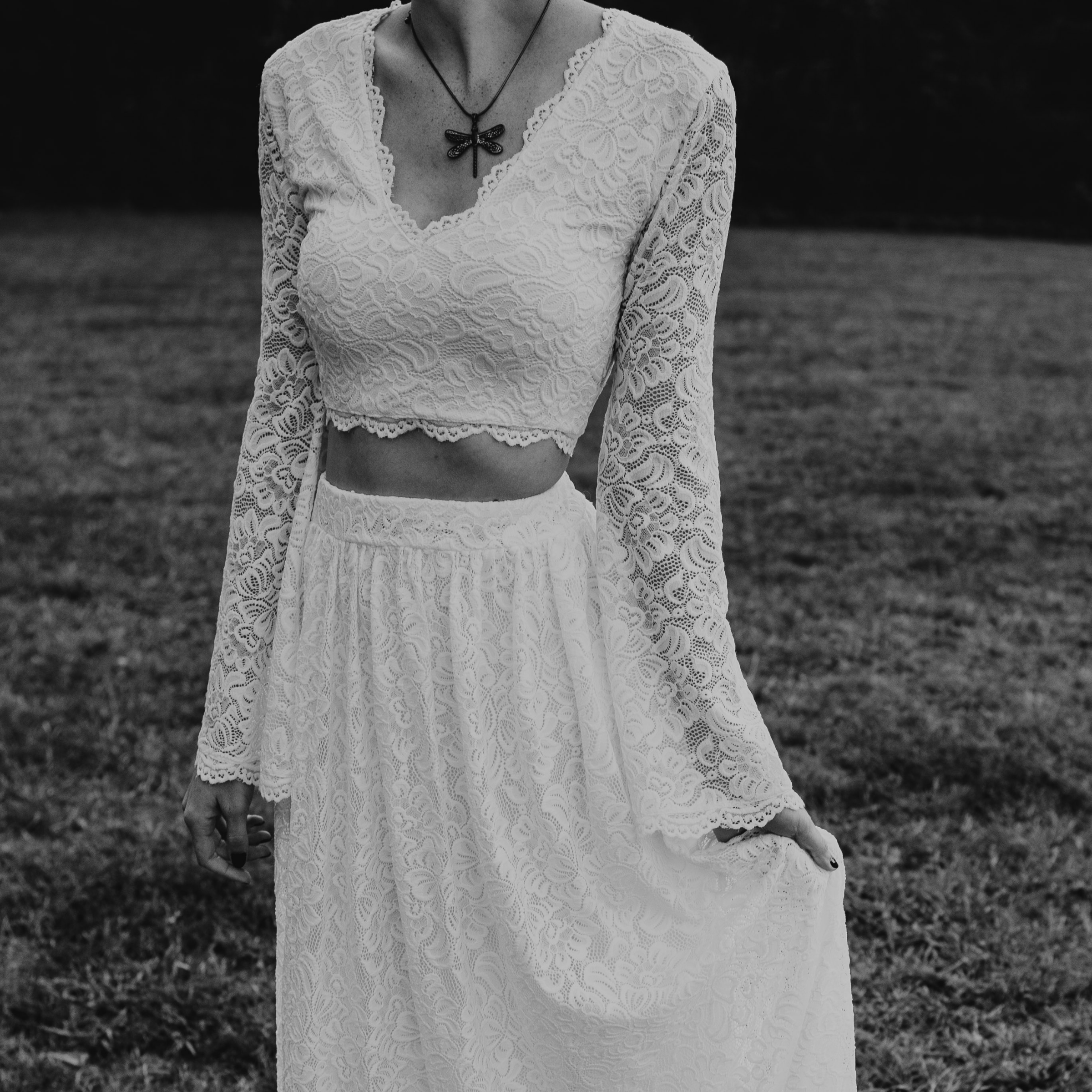 Ivory lace two-piece wedding dress with bell sleeves, featuring a cropped top and flowing skirt. A bohemian bridal outfit.
