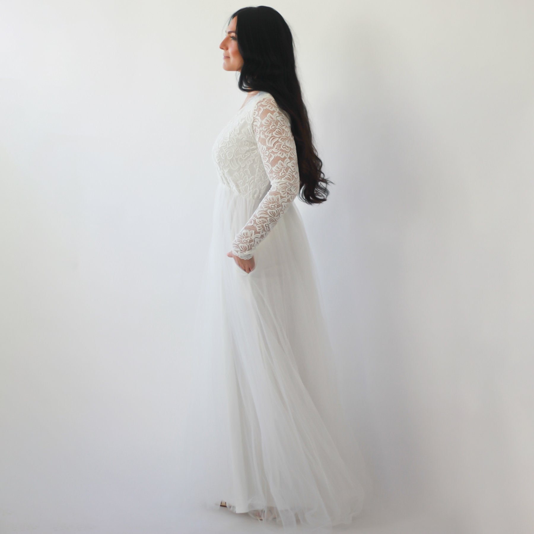 Woman wearing an Arvalie Tulle and Lace Wedding Gown with long sleeves and a flowing tulle skirt, designed for plus-size figures.