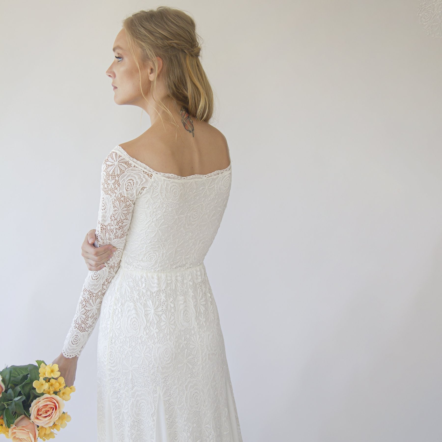 Woman wearing Evianne off-shoulder lace wedding gown with sleeves, showcasing floral lace and mermaid silhouette.