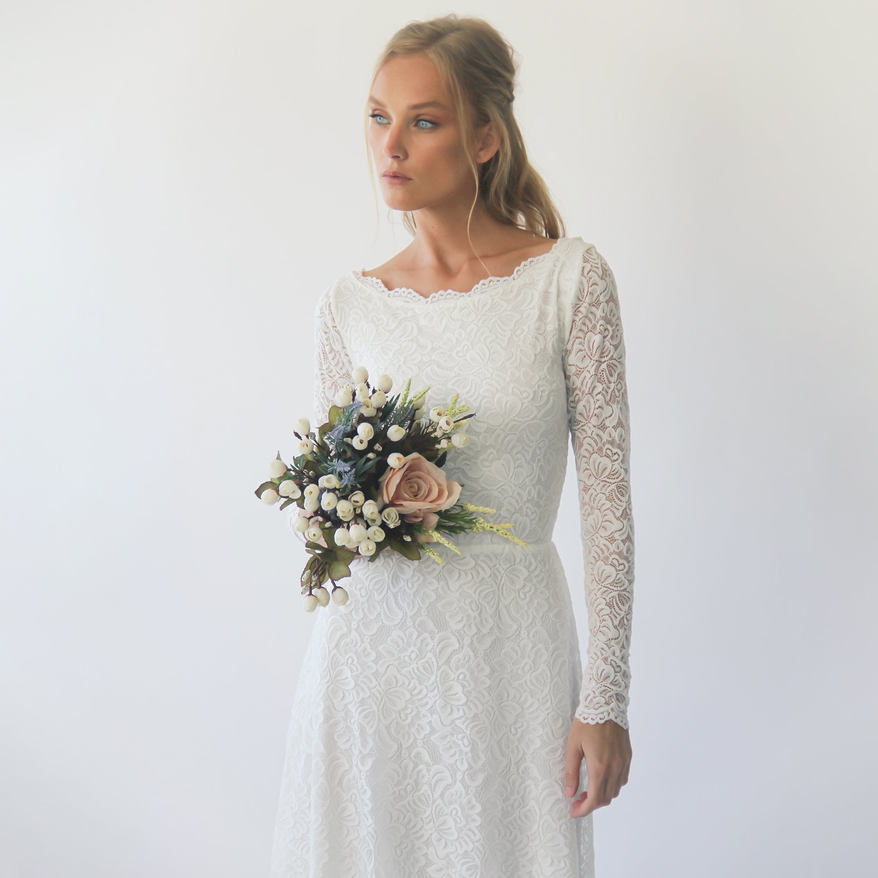 Woman in Belloria Modest Lace Wedding Dress with bouquet, featuring floral sash and boat neckline, epitomizing elegance and romance.