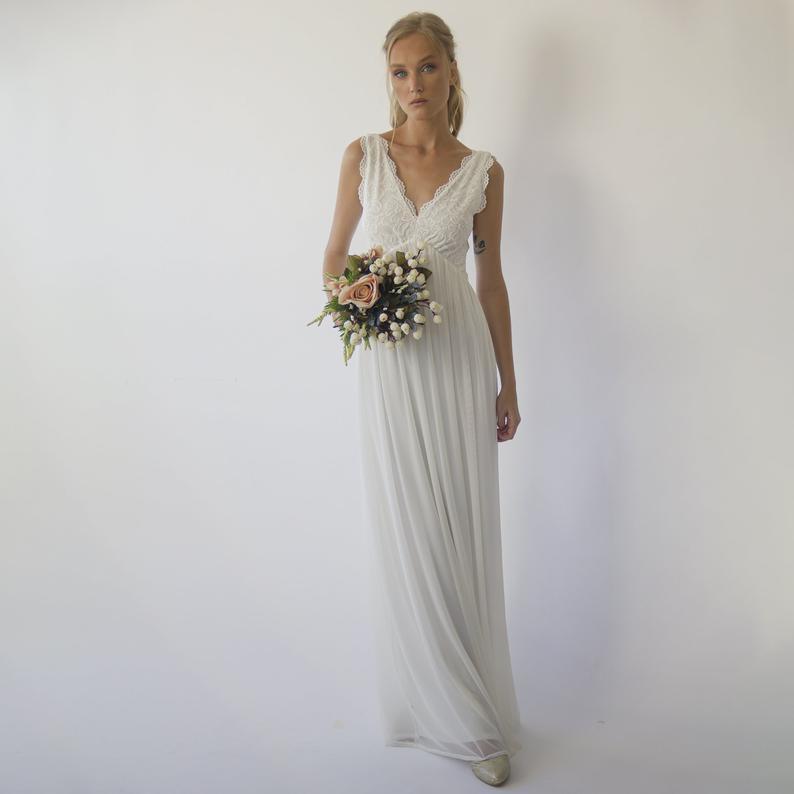 Bride wearing an Ivorelle open-back wedding gown with lace bodice and chiffon skirt, holding a bouquet, perfect for garden ceremonies.
