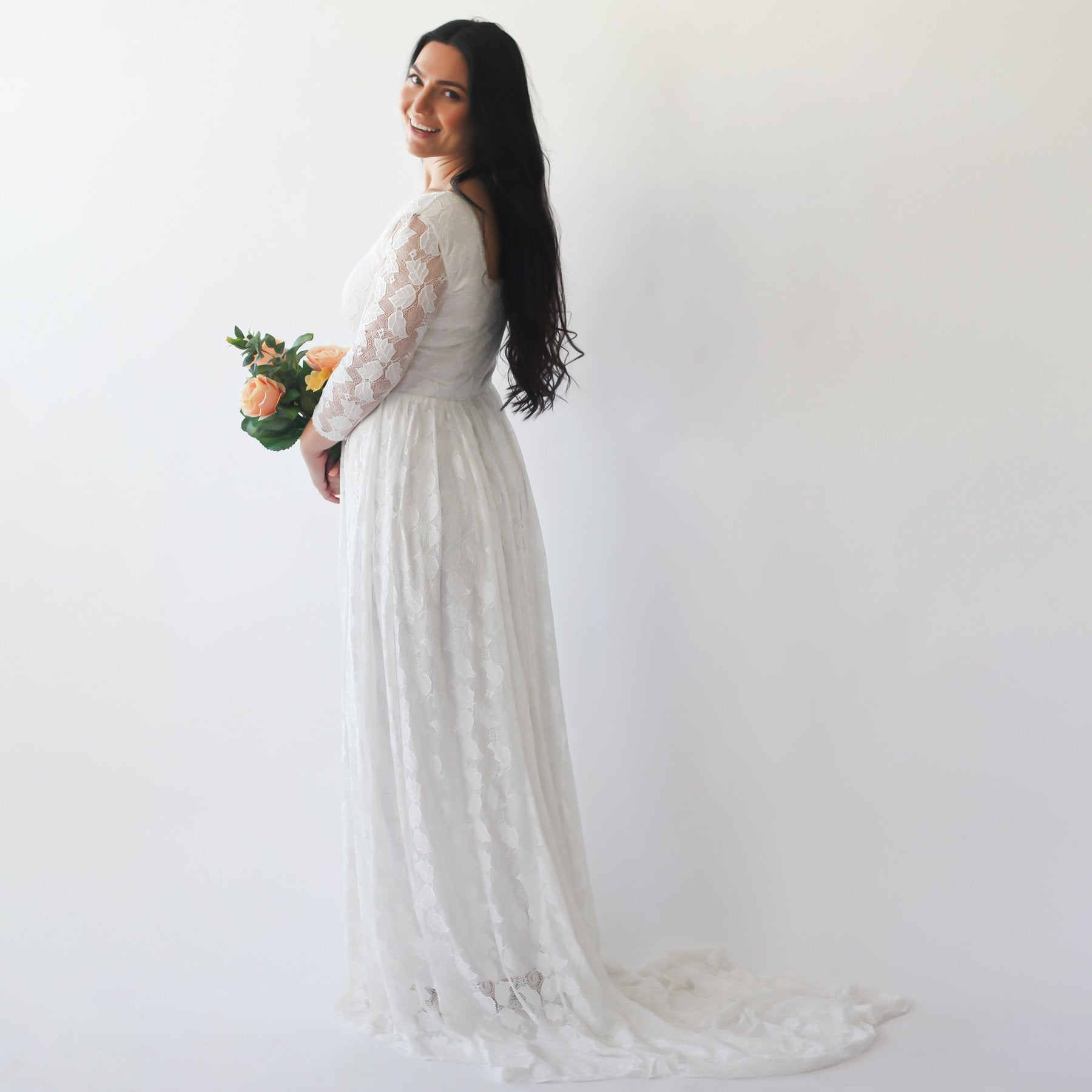 Woman in ivory square neck wedding dress with lace train holding roses, showcasing elegant simplicity and timeless style.