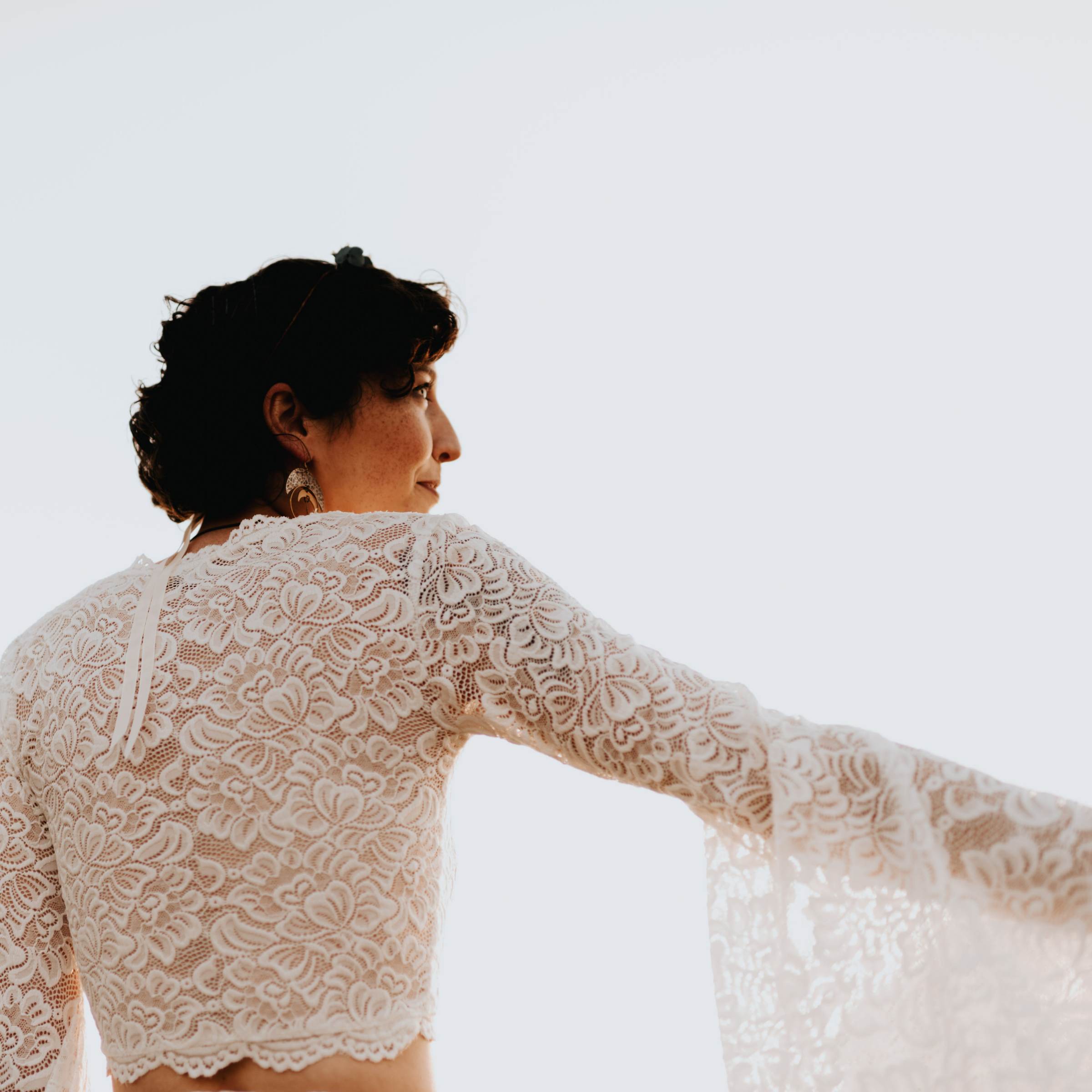 Ivory lace cropped top with bell sleeves, featuring intricate floral patterns, part of Avelyne's two-piece wedding ensemble.