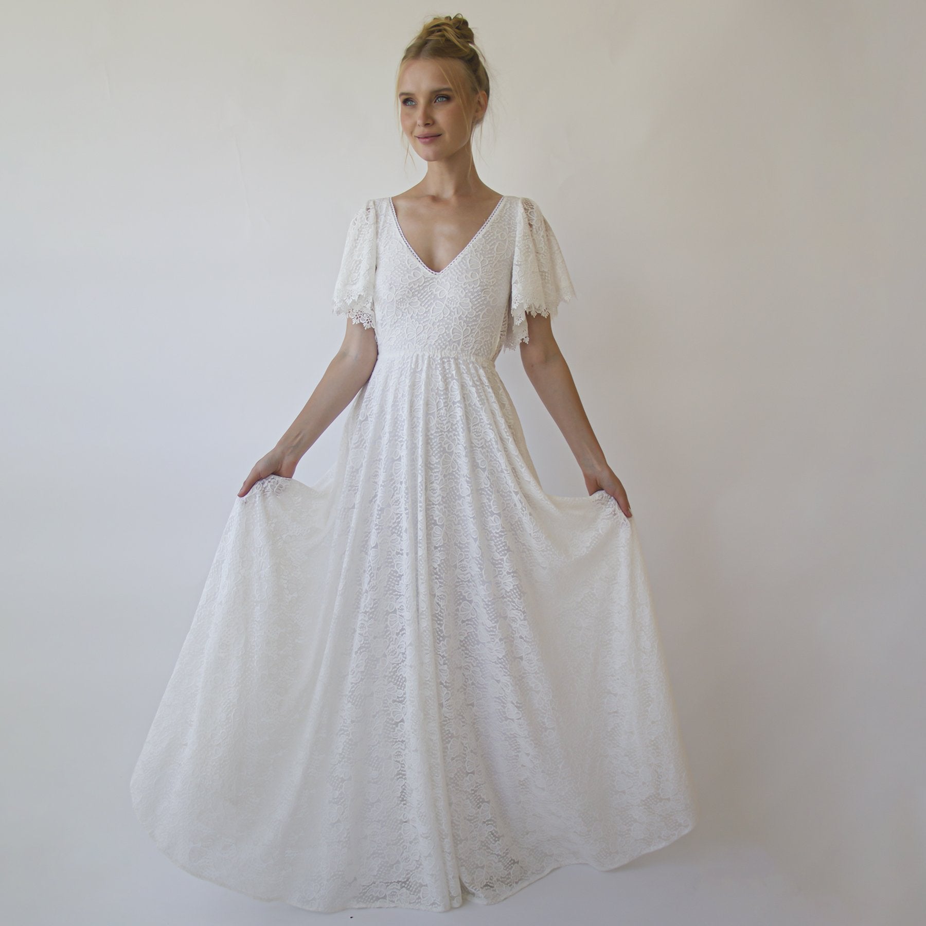 Woman wearing Solvene Open Back Lace Wedding Dress with butterfly sleeves and bohemian lace details, showcasing its flowy, romantic design.