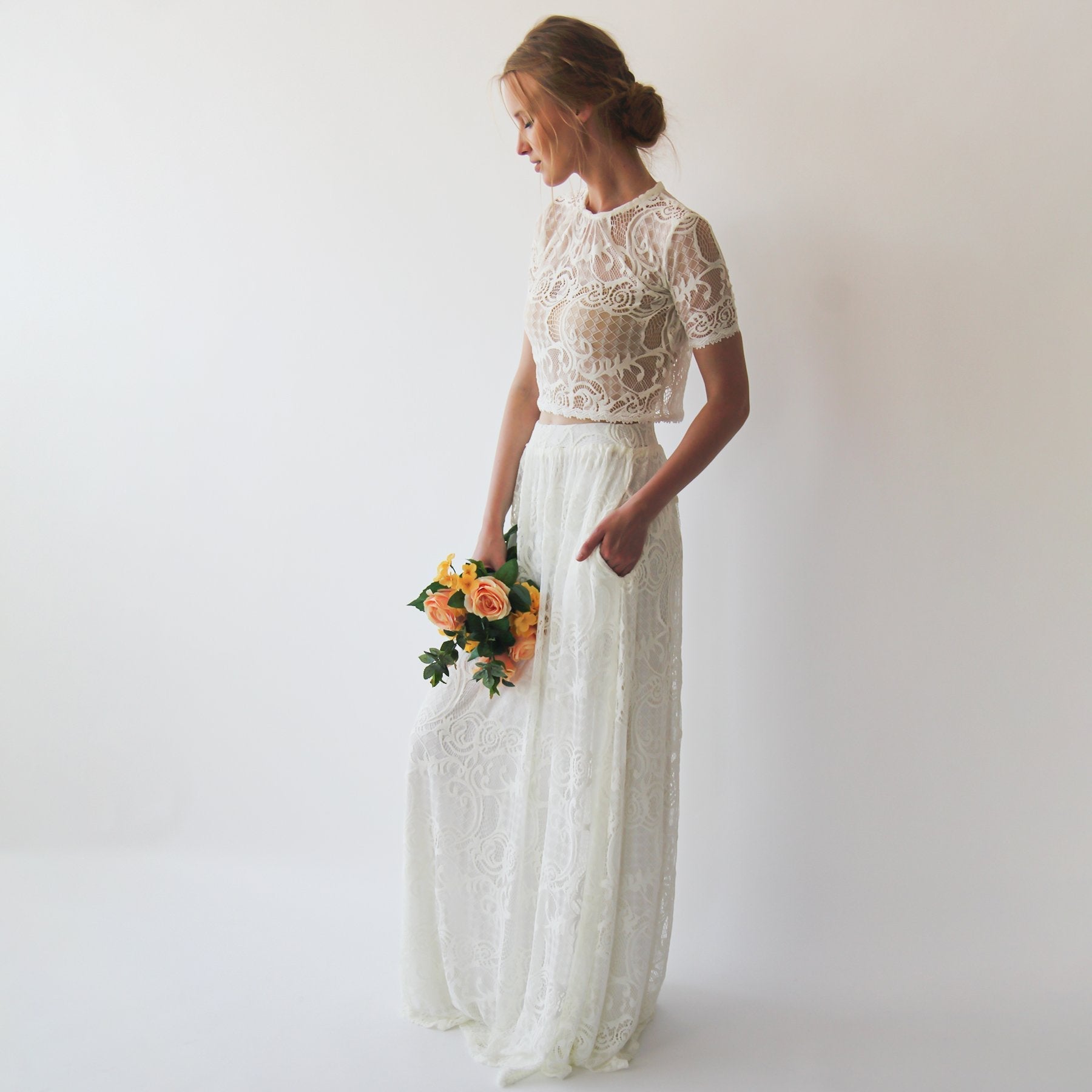 Bride wearing Lyssara two-piece wedding dress with lace skirt, featuring lace crop top and flowing skirt, holding a bouquet.
