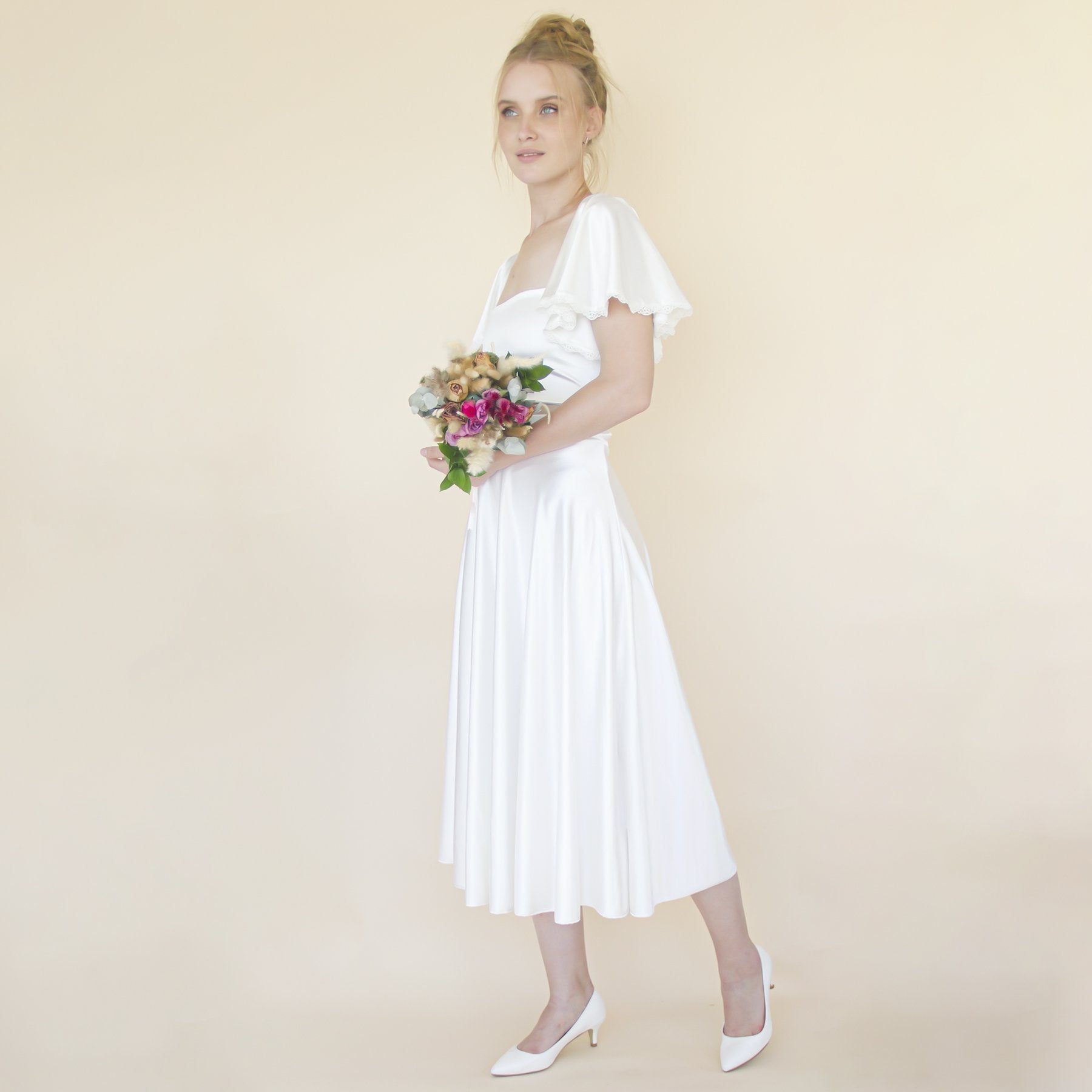 Loraine ivory satin midi wedding skirt with elegant drape, worn by modern bride holding bouquet, ideal for weddings or city events.