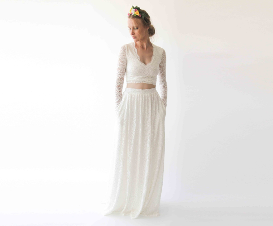 Bride wearing Elarin long sleeve bridal lace top with V neckline, paired with a flowing skirt, featuring a floral headpiece.