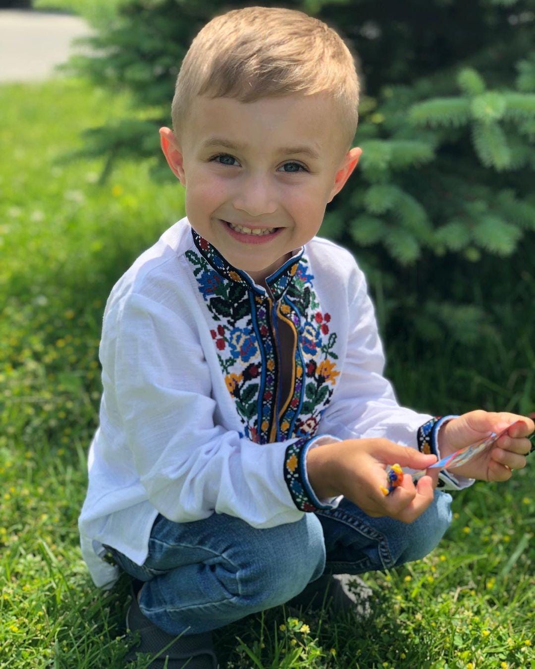 Boys' embroidered linen shirt featuring traditional Ukrainian Vyshyvanka designs, worn by a smiling child outdoors.