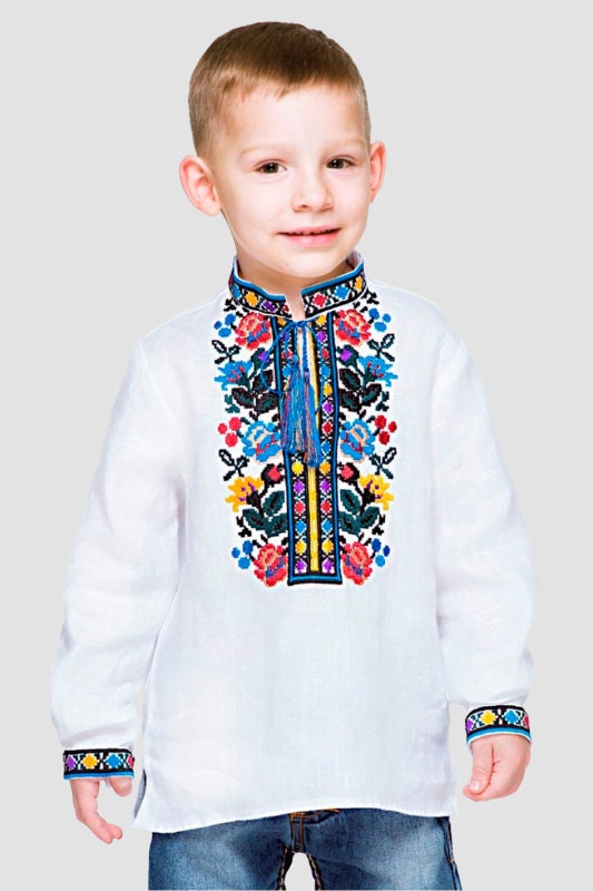 Boy wearing embroidered linen shirt with traditional Ukrainian vyshyvanka floral pattern, vibrant folk style on white fabric.