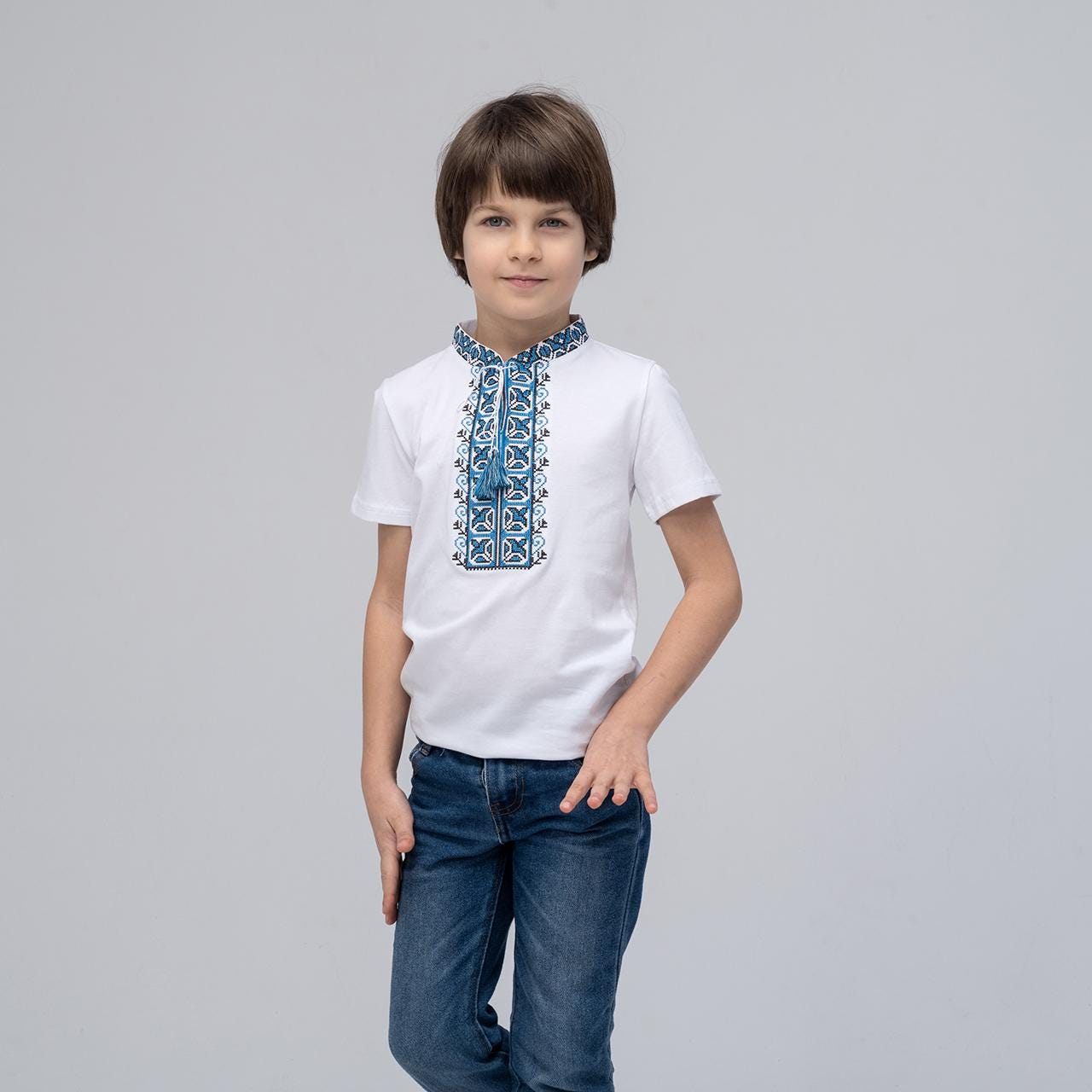 Boy wearing a blue embroidered Ukrainian vyshyvanka shirt with short sleeves and geometric designs, ideal for summer.