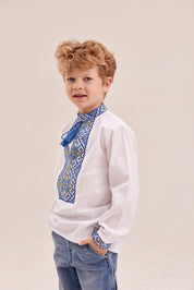 Boy wearing white Ukrainian embroidered shirt with blue ornament and tassels.