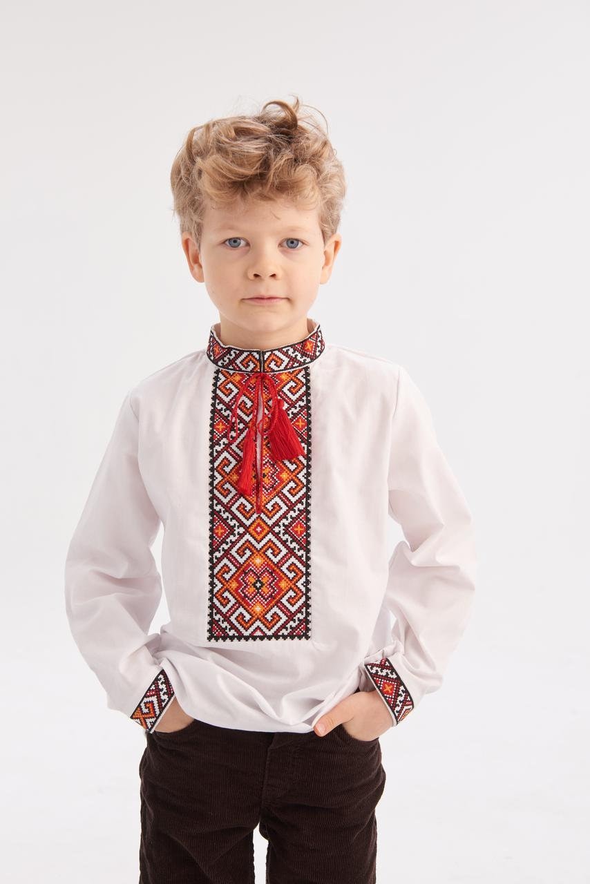 Boy wearing Ukrainian embroidered shirt 'Miron' in white cotton with red and black geometric motifs, suitable for ages 5-12.