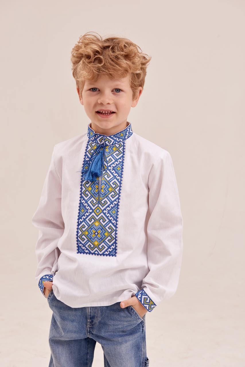 Young boy wearing a white Ukrainian embroidered shirt with blue and yellow geometric patterns, ideal for cultural events and festive occasions.