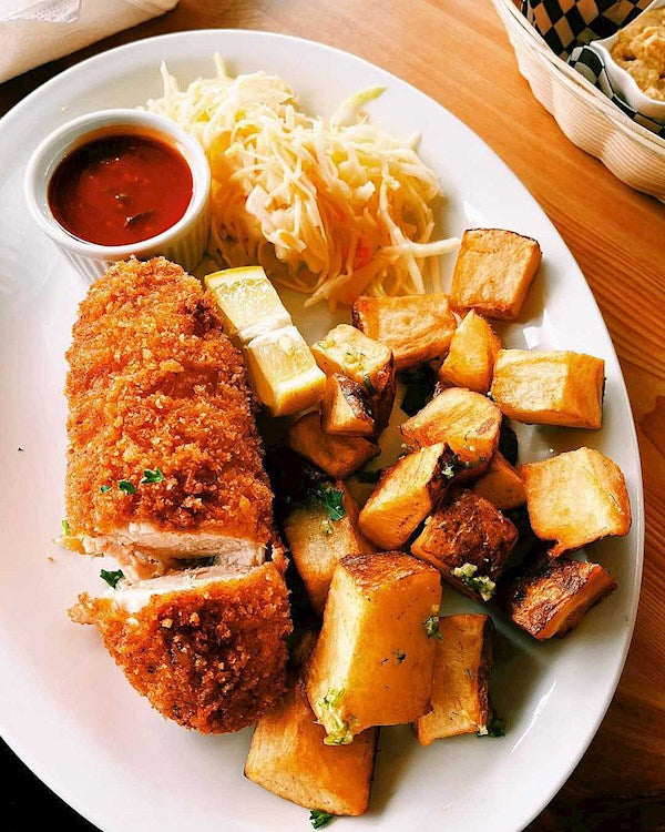 Plate with Kotleta Po-Kyivsky, crispy potatoes, coleslaw, and dipping sauce; classic Ukrainian chicken cutlet meal.