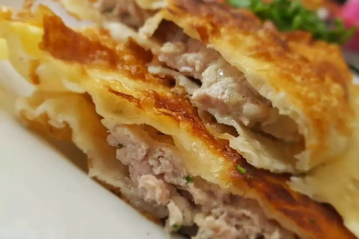 Close-up of homemade Ukrainian chebureki, crispy deep-fried pastries with juicy beef filling, showcasing a golden, crunchy texture.