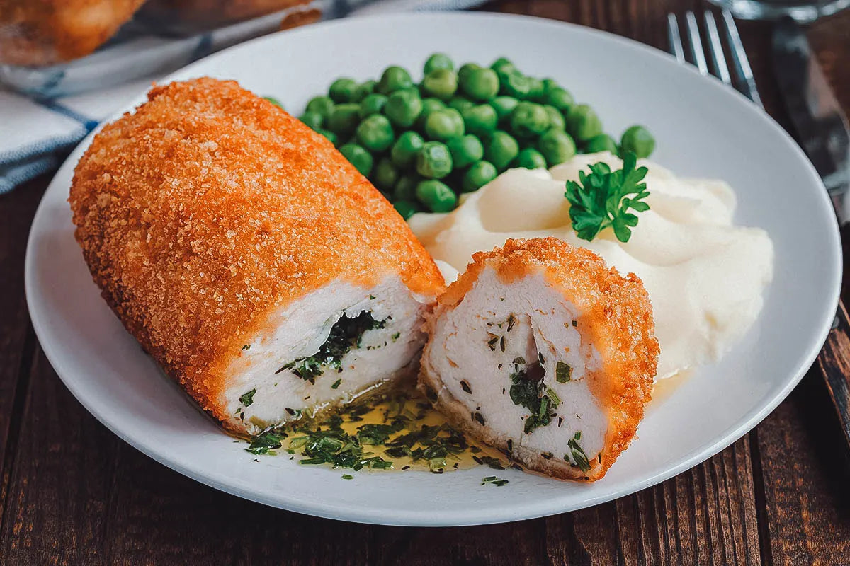 Ukrainian Chicken Kyiv cutlet with golden breading served with peas and mashed potatoes on a plate