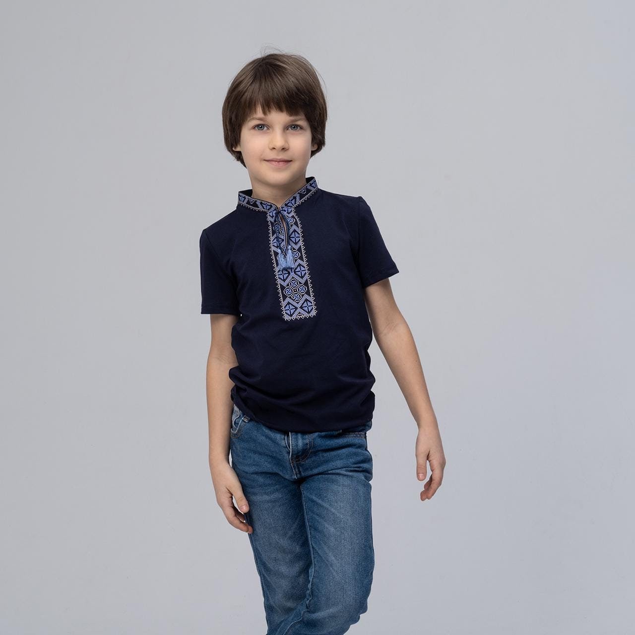 Boy wearing a dark blue T-shirt with traditional Ukrainian embroidery, featuring Kozatska pattern, symbolizes peace and well-being.