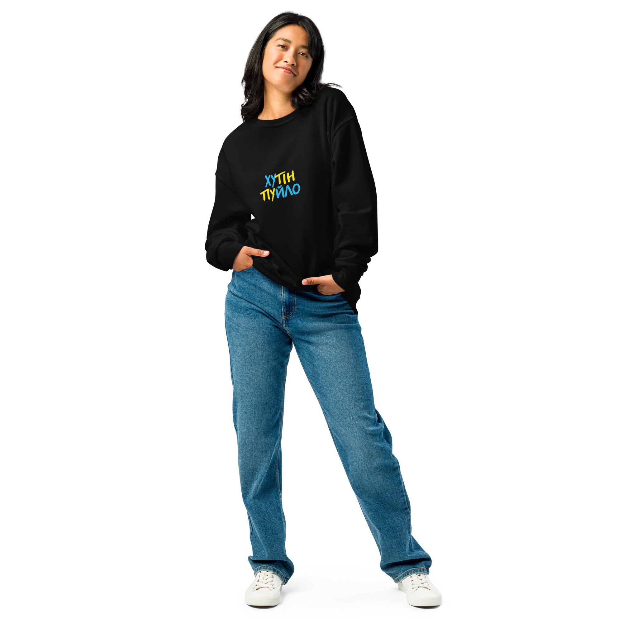 Woman wearing a black "ХУТІН ПУЙЛО" T-shirt with trident logo, paired with jeans and white sneakers, showcasing casual style.