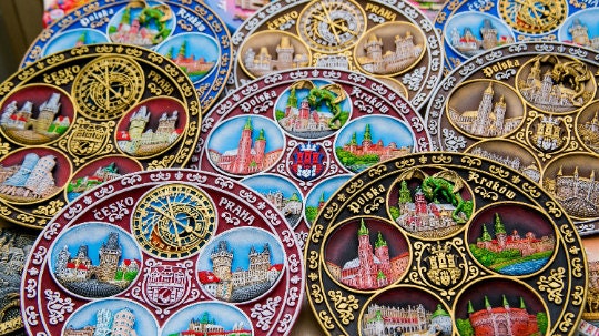 Colorful hand-painted souvenir plates displaying European city landmarks in intricate designs.