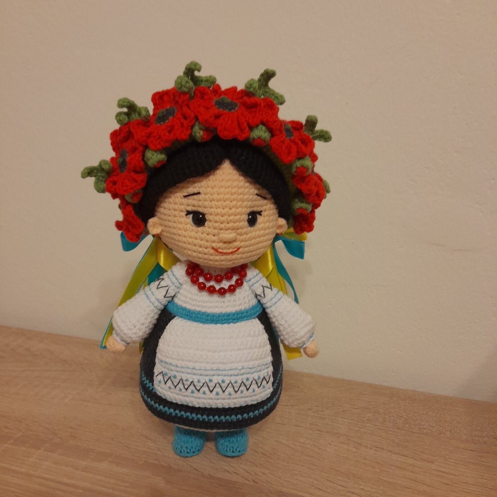 Crochet Ukrainian doll in traditional attire with red flowers, handmade souvenir gift, cultural craftsmanship.