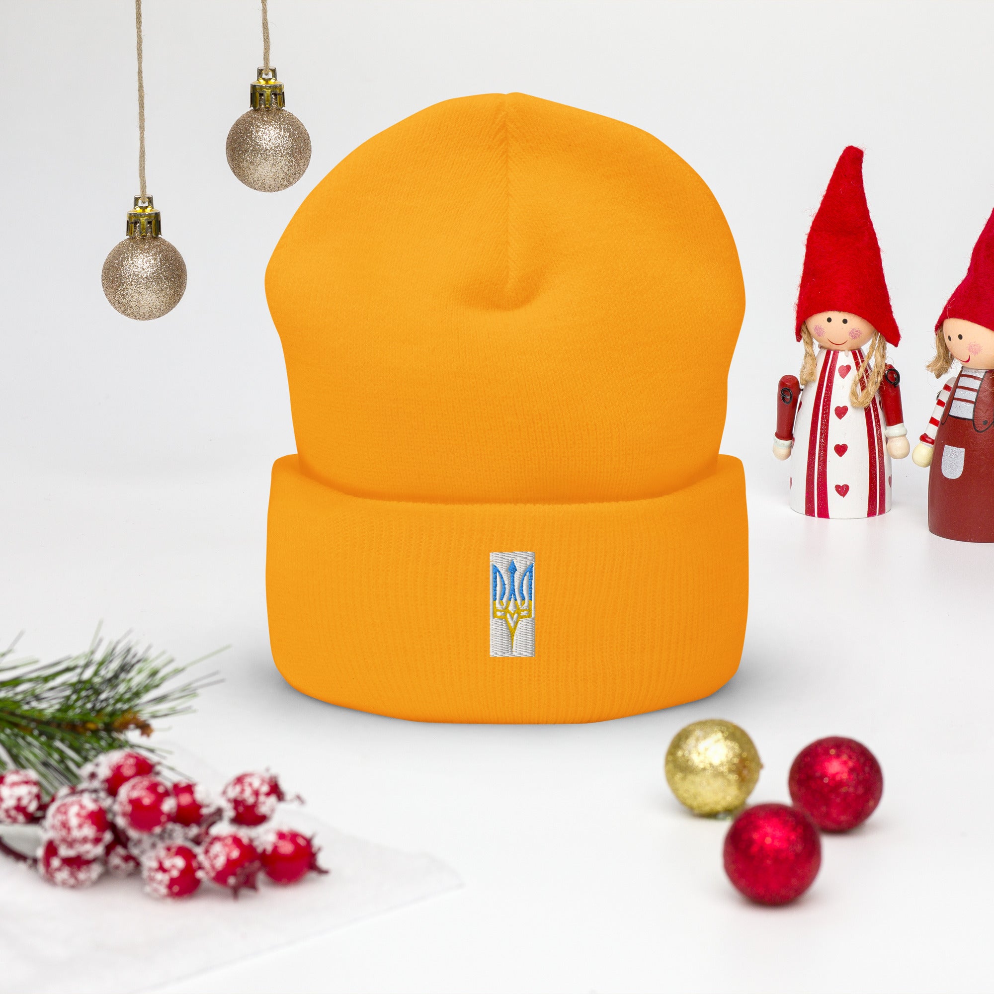 Unisex cuffed beanie with embroidered Ukrainian Tryzub emblem on a holiday-themed background, showcasing style and Ukrainian pride.