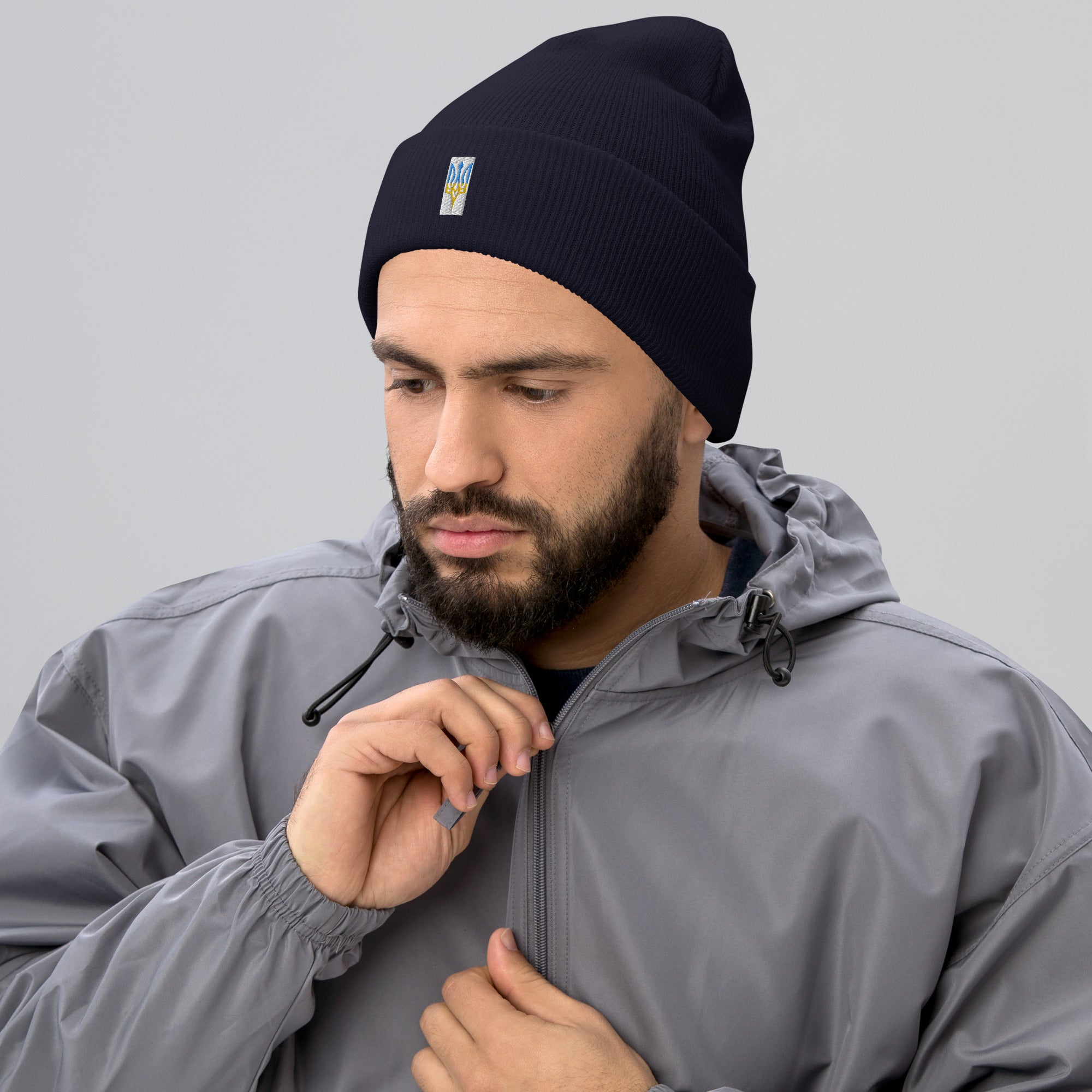 Unisex cuffed beanie with embroidered Ukrainian Tryzub worn by man in gray jacket, showcasing stylish blue and yellow design.