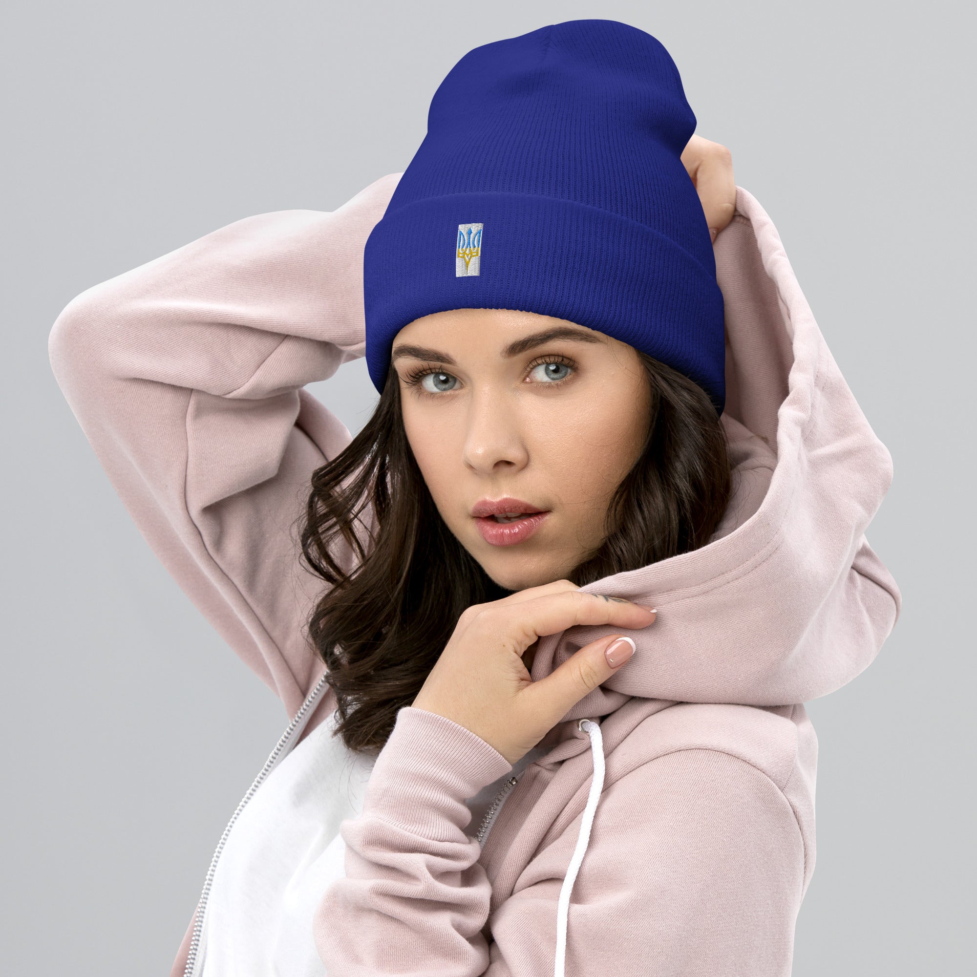 Woman wearing blue unisex cuffed beanie with embroidered Ukrainian Tryzub emblem for style and warmth.