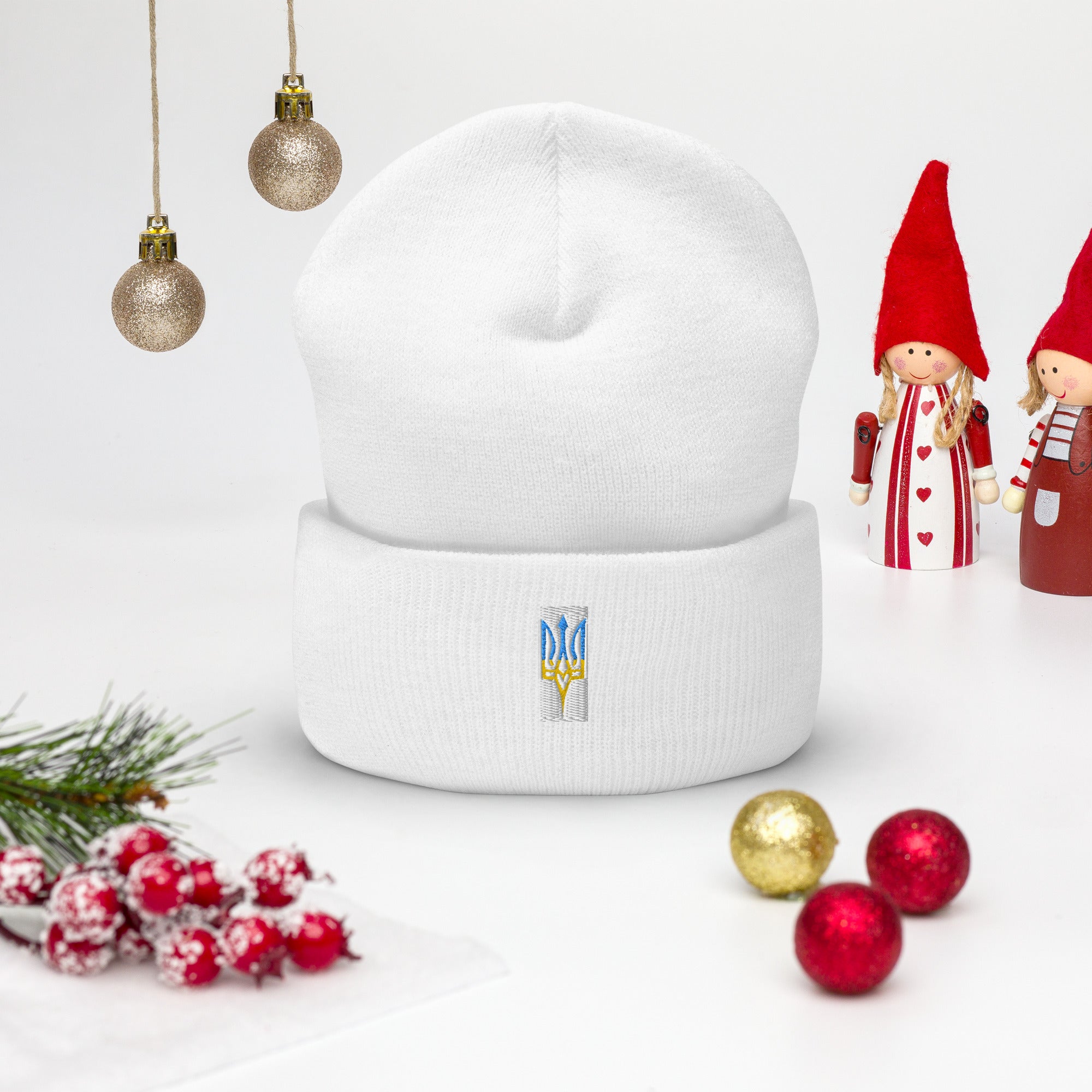 White unisex beanie with embroidered Ukrainian Tryzub emblem displayed among festive decorations.