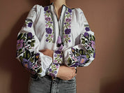 Woman wearing custom Ukrainian Vyshyvanka blouse with purple floral embroidery on white fabric.