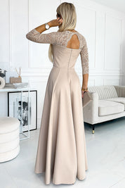 Woman wearing Alviera Beige Lace Maxi Gown with open back design, standing in elegant room setting.