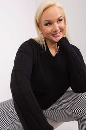Smiling woman wearing a black plus size Mirella Textured Knit Sweater and plaid pants, showcasing cozy and elegant style.