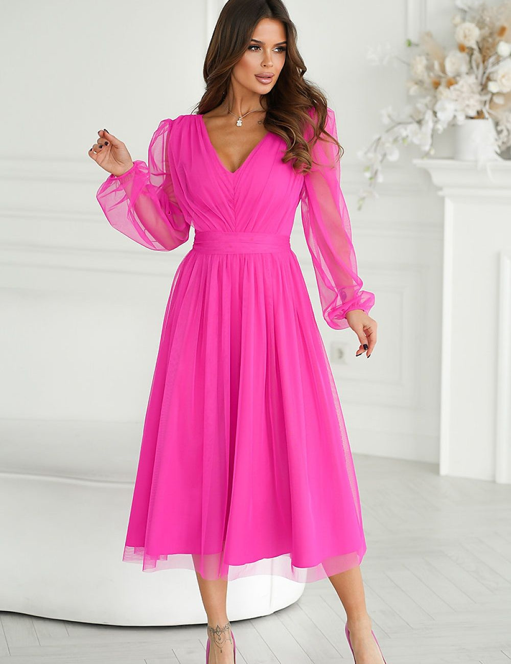 Woman wearing pink Marleia Mesh-Layered Evening Midi Dress with elegant sheer sleeves and flared skirt in stylish room setting.